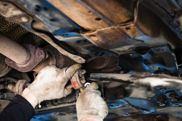 mechanic dismantles old muffler suspension on car
