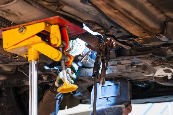 Welder fixes silencer on exhaust pipe — Stock Photo, Image