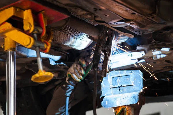 welder welds silencer on exhaust pipe