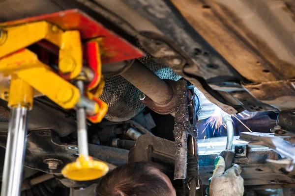 Trabajador suelda el silenciador en el coche por soldadura de argón —  Fotos de Stock