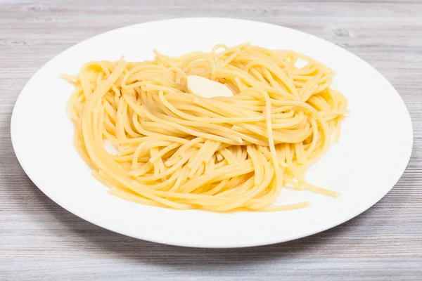 Pasta med smör på vit tallrik på grått bord — Stockfoto