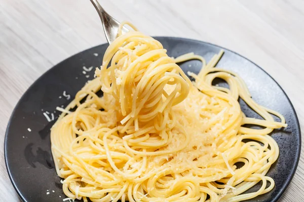 Tenedor envuelto por espaguetis sobre plato negro — Foto de Stock