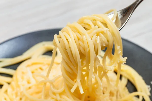 Tenedor con espaguetis de cerca sobre plato negro — Foto de Stock