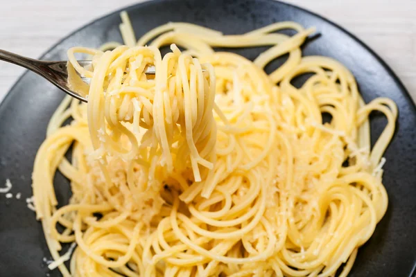 Top view of fork with spaghetti over black plate — Stock Photo, Image