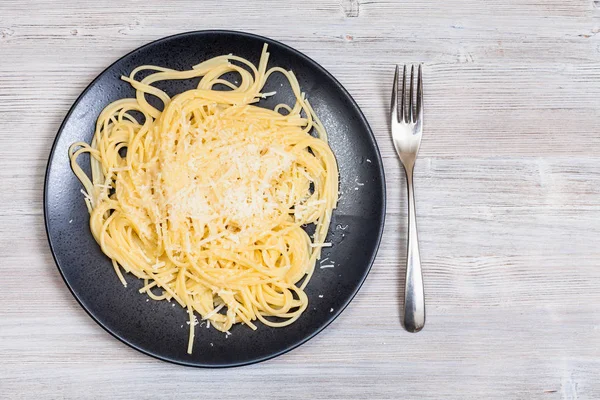 Pasta con mantequilla y queso y tenedor en gris —  Fotos de Stock