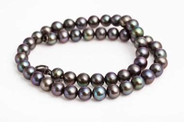 Beyaz üzerine doğal siyah incilerden sarılmış kolye.