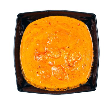 Hint mutfağı - beyaz arka planda izole edilmiş siyah kasede tavuk tikka masala 'nın (baharatlı köri soslu kızarmış tavuk parçaları) üst görüntüsü