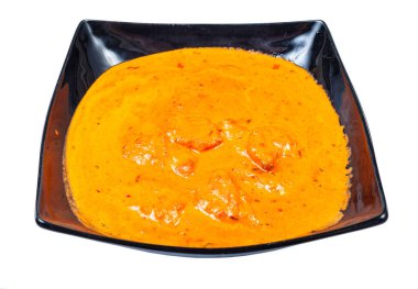 Hint mutfağı - beyaz arka planda izole edilmiş siyah kasede tavuk tikka masala (baharatlı köri soslu kızarmış tavuk parçaları)