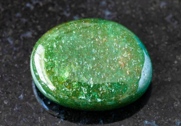 地質学的コレクションからの天然鉱物のサンプルの閉鎖 インドからの黒御影石の背景に研磨緑のアベンチュリン宝石石 — ストック写真