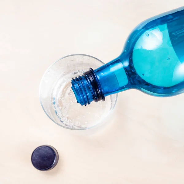 Top View Pouring Sparkling Mineral Water Blue Plastic Bottle Glass — Stock Photo, Image