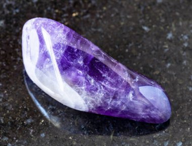 Namibya 'dan siyah granit arka planda jeolojik koleksiyondaki doğal mineral örneklerine yakın çekim - yuvarlanmış Ametist kayası