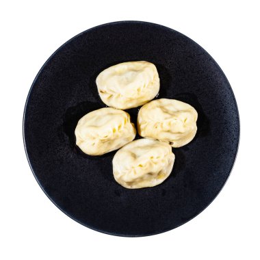 Kaynamış Manti 'nin üst görünümü (Türk mutfağındaki hamur köftesi türü) beyaz arkaplanda izole edilmiş siyah tabak üzerinde