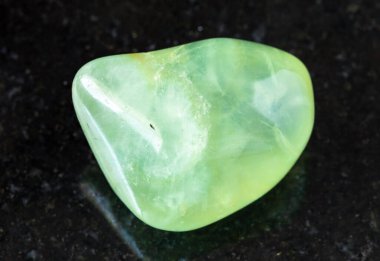 Jeolojik koleksiyondaki doğal mineral örneğinin yakın çekimi - Mali Cumhuriyeti 'nin siyah granit arka planında cilalanmış Prehnite kayası