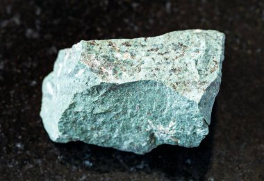 Jeolojik koleksiyondaki doğal mineral numunesinin yakın çekimi. Siyah granit zemin üzerinde sert Tinguaite kayası.