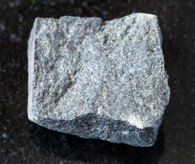 Jeolojik koleksiyondaki doğal mineral örneklerinin yakın çekimi. Siyah granit arka plandaki sert Gabbro kayası.