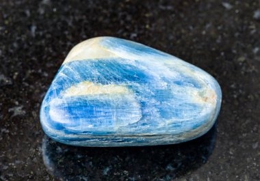 Jeolojik koleksiyondaki doğal mineral örneklerinin yakın çekimi - Brezilya, Minas Gerais 'den siyah granit arka planda cilalanmış Kyanite kayası