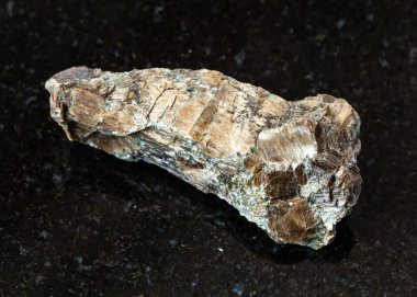 Jeolojik koleksiyondaki doğal mineral örneklerine yakın çekim - siyah granit zemin üzerinde kaba Bronzit (Enstatite) kayalar, Rai-Iz kütlesi, Kutup Uralları, Rusya