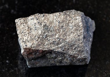Jeolojik koleksiyondaki doğal mineral örneklerinin yakın çekimi - Rusya 'nın Kola Yarımadası' ndan siyah granit zemin üzerinde cilalanmamış Pyrrhotite (Pyrotite) kayası