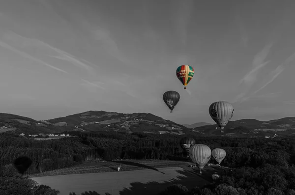 Částečně barevné horkovzdušné balónky vzlétají v šedé — Stock fotografie