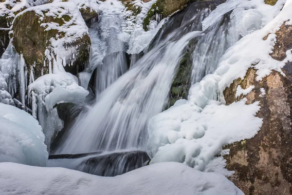 Cachoeira com rochas e neve nas montanhas — Fotografia de Stock