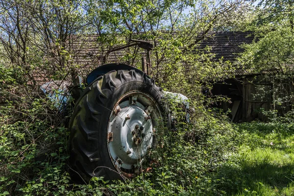 Overgrown tractor at a farm — 스톡 사진