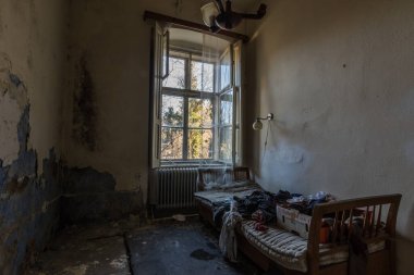 Dağlarda yatağı ve açık penceresi olan terk edilmiş bir otel odası.