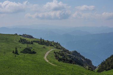 Dağlarda yeşil çayırları ve kayaları olan yürüyüş patikaları.