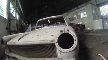 Terk edilmiş büyük salonda eski bir araba.