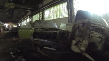 Terk edilmiş büyük salonda bir sürü eski araba var.