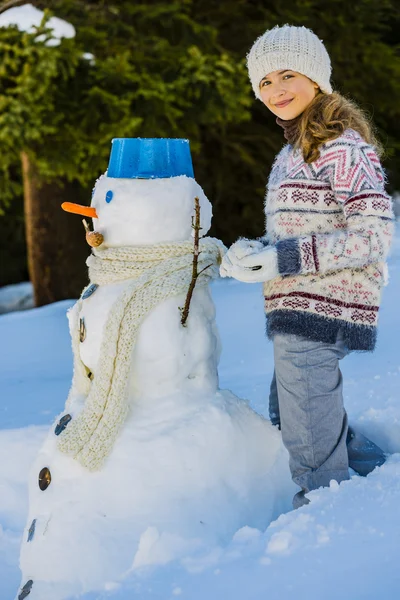 快乐微笑的少女，玩一个雪人在白雪皑皑的胜利 — 图库照片