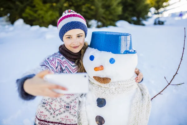 Feliz sonrisa adolescente tomando selfie con un muñeco de nieve en un sno —  Fotos de Stock