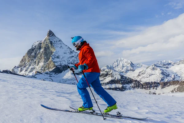 Ski touring man reaching the top in Swiss Alps. Matterhorn in th