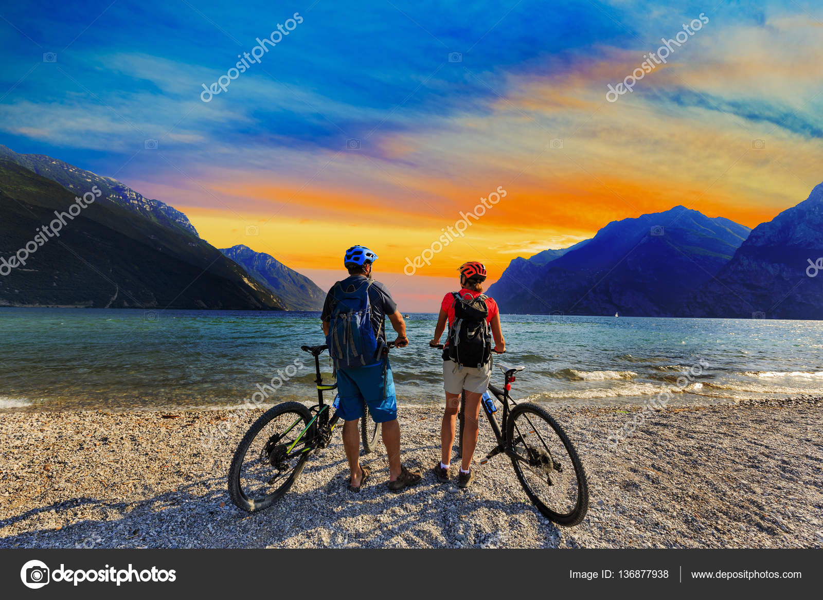 VTT, couple avec vélos au coucher du soleil sur le lac de Garde