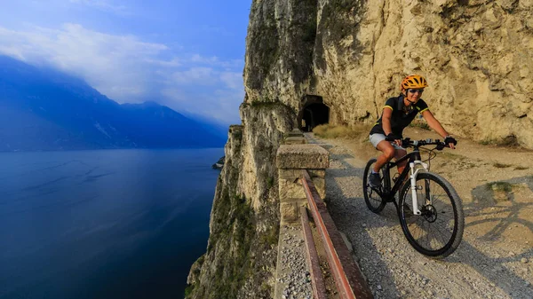 Mountainbiken bei Sonnenaufgang Frau über dem Gardasee auf Weg sentiero della ponale, riva del garda, italien — Stockfoto