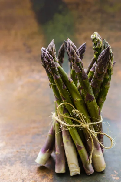 Bos van verse groene asperges op een rustieke achtergrond. — Stockfoto