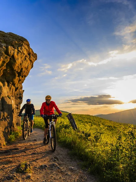 Horská cykloturistika ženy a muže na koni na kolech v západu slunce mountain — Stock fotografie