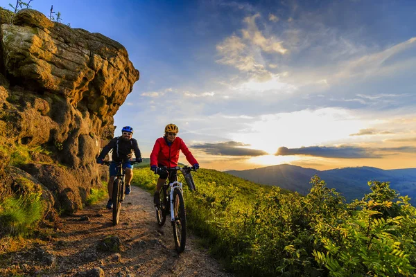 Mountain biking women and man riding on bikes at sunset mountain — Stock Photo, Image