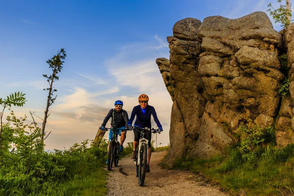 山の自転車に乗る女性とマン日没山でバイクに乗って — ストック写真