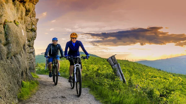 山の自転車に乗る女性とマン日没山でバイクに乗って — ストック写真