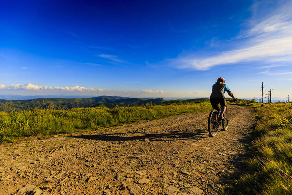 Mountain biking women riding on bike in summer mountains forest 