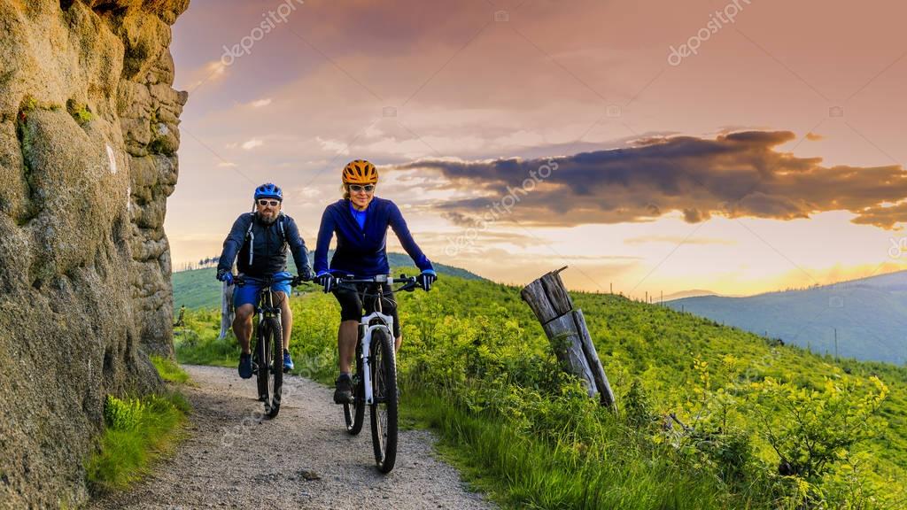 Mountain bike donne e uomo in sella a biciclette al tramonto