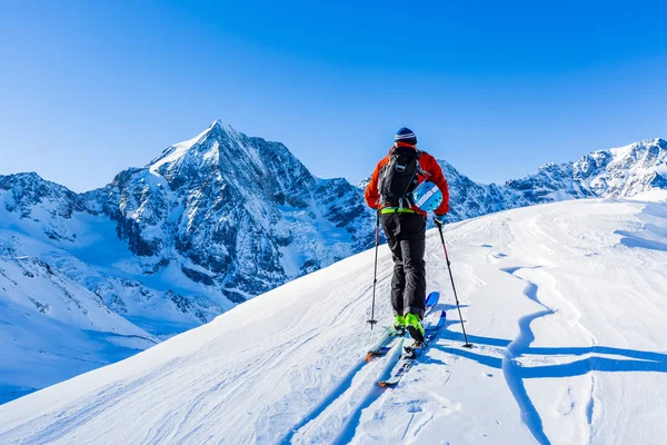 Ski de montagne marchant le long d'une crête enneigée avec des skis dans le bac — Photo