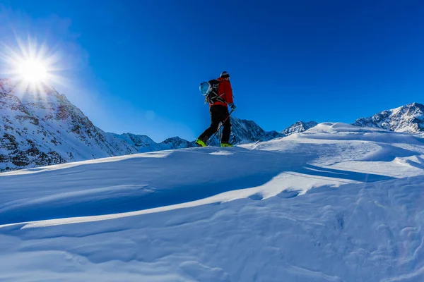 Esquí de montaña caminando a lo largo de una cresta nevada con esquís en el bac —  Fotos de Stock