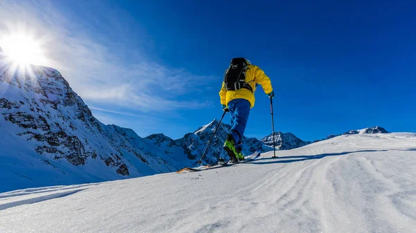 Mountain ski walking up along a snowy ridge with skis in the bac — Stock Photo, Image