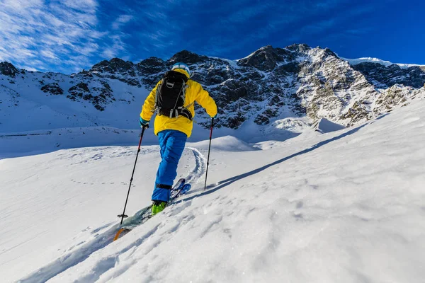 Mountain ski gå upp längs en snöig bergskam med skidor i bac — Stockfoto