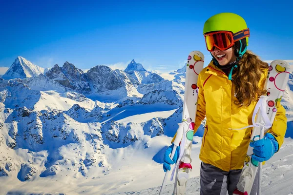 Skiër tiener langs een besneeuwde bergkam met ski's. In de achtergrond blauw — Stockfoto