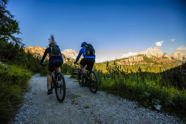 Mountain biking couple with bikes on track at sunset, Cortina d'