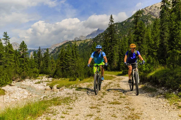 Turistas de bicicleta em Cortina d 'Ampezzo, deslumbrantes montanhas rochosas — Fotografia de Stock