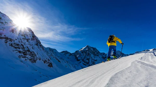 Esqui de montanha caminhando ao longo de um cume nevado com esquis no bac — Fotografia de Stock