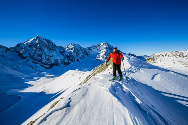 Ski de montagne marchant le long d'une crête enneigée avec des skis dans le bac — Photo